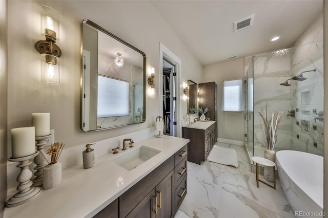 bathroom with a marble finish shower, marble finish floors, a freestanding tub, recessed lighting, and two vanities