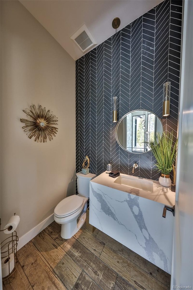 bathroom with tile walls, toilet, wood finished floors, and a shower