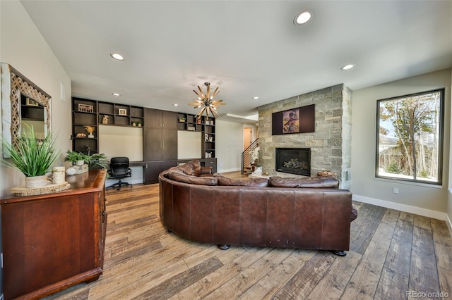 living room featuring a desk, hardwood / wood-style flooring, a stone fireplace, recessed lighting, and baseboards