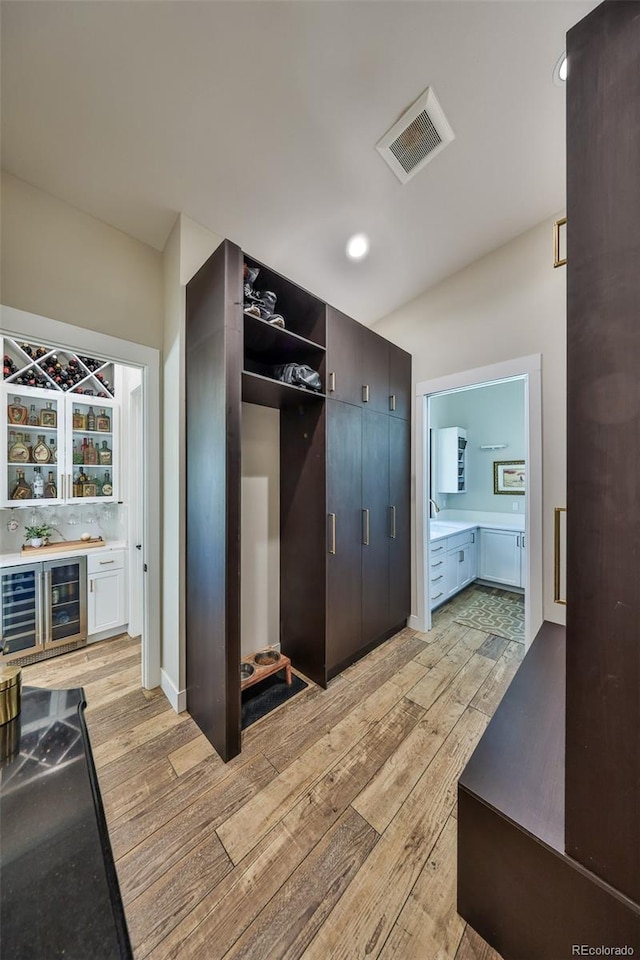 mudroom featuring a bar, light wood-style flooring, and beverage cooler