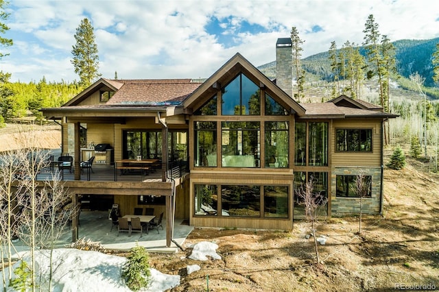 back of house featuring a patio area, a chimney, and a deck with mountain view