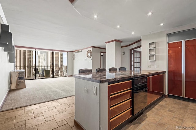 kitchen with dark stone counters, built in fridge, oven, carpet flooring, and ornamental molding