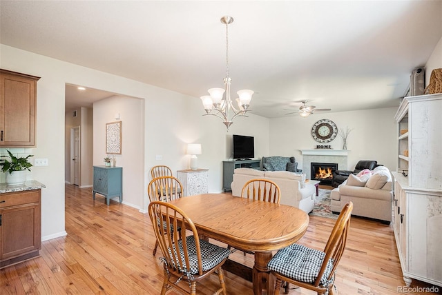 3406 Quicksilver Rd, Frederick, CO 80516 - dining space featuring a ceiling fan, light wood-style flooring, a glass covered fireplace, and a chandelier