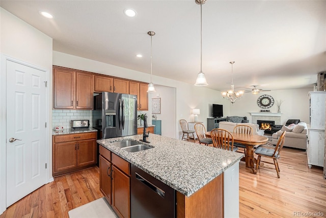 3406 Quicksilver Rd, Frederick, CO 80516 - kitchen with appliances with stainless steel finishes, open floor plan, a warm lit fireplace, brown cabinetry, and recessed lighting