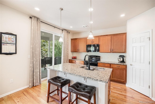 3406 Quicksilver Rd, Frederick, CO 80516 - kitchen featuring black appliances, decorative backsplash, light wood-style floors, brown cabinets, and recessed lighting