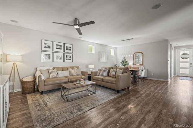 living room with dark wood-type flooring, baseboards, and ceiling fan