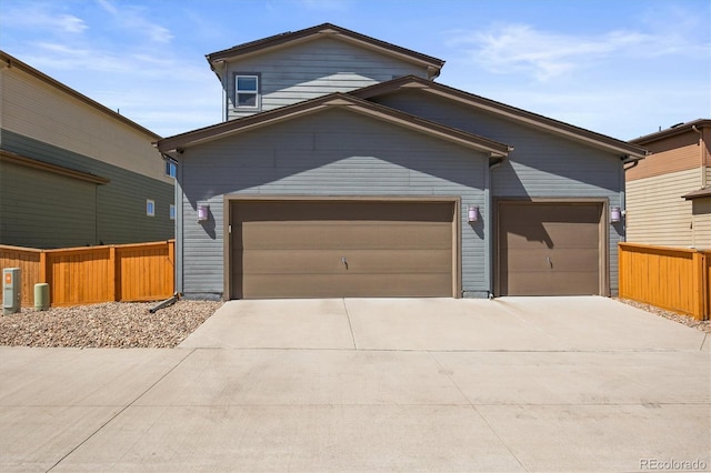 view of front of house with concrete driveway, an attached garage, and fence