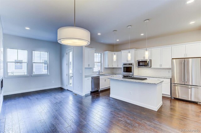 kitchen featuring stainless steel appliances, white cabinets, a center island, and tasteful backsplash