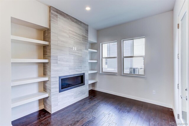 unfurnished living room featuring tile walls, built in shelves, a high end fireplace, and wood-type flooring