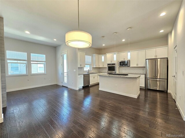 kitchen featuring white cabinets, a center island, dark wood-type flooring, and stainless steel appliances