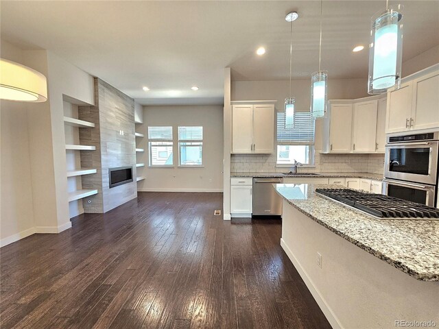 kitchen featuring appliances with stainless steel finishes, dark wood-type flooring, light stone countertops, and a healthy amount of sunlight