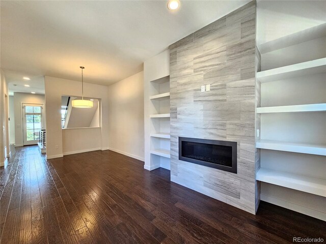 unfurnished living room featuring built in features, a fireplace, dark hardwood / wood-style floors, and tile walls