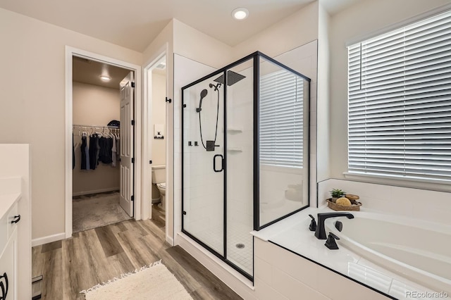 5134 Queen Ct, Arvada, CO 80002 - bathroom with wood finished floors, a stall shower, a garden tub, a walk in closet, and vanity