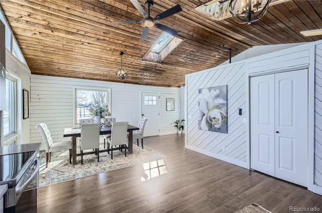 dining room featuring wood ceiling, dark hardwood / wood-style floors, wooden walls, ceiling fan, and vaulted ceiling with skylight