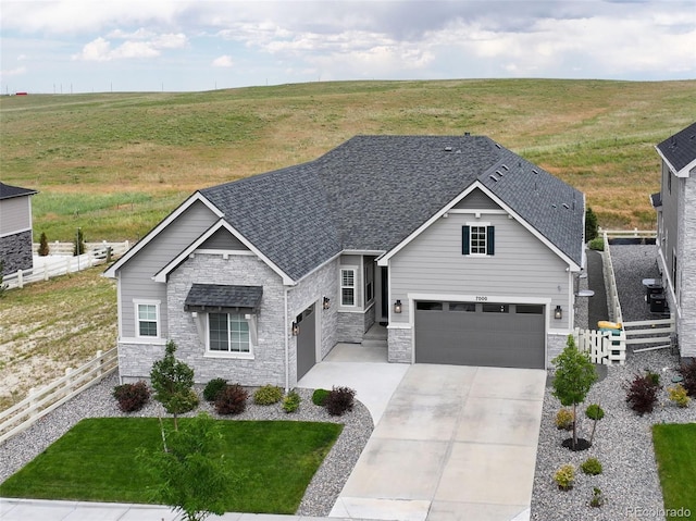 7000 S White Crow Way, Aurora, CO 80016 - view of front of home featuring stone siding, concrete driveway, roof with shingles, and a garage