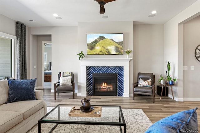 7000 S White Crow Way, Aurora, CO 80016 - living room featuring wood finished floors, a tiled fireplace, a ceiling fan, and recessed lighting