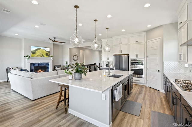 7000 S White Crow Way, Aurora, CO 80016 - kitchen with a ceiling fan, tasteful backsplash, a tile fireplace, white cabinets, and light wood-style flooring