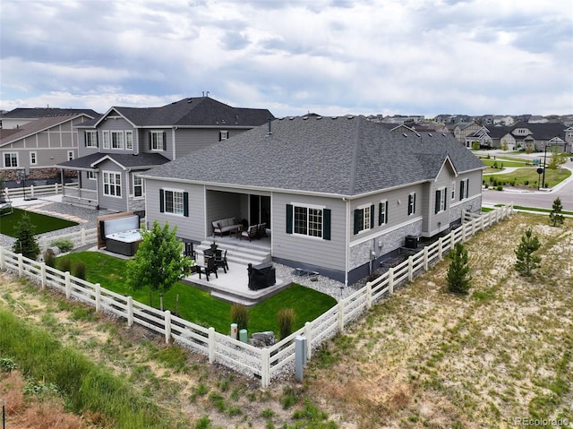 7000 S White Crow Way, Aurora, CO 80016 - rear view of house featuring a fenced backyard, a residential view, a shingled roof, a patio, and a hot tub
