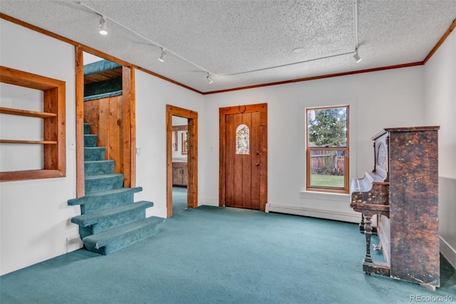 carpeted foyer entrance with a textured ceiling, ornamental molding, a baseboard heating unit, and track lighting