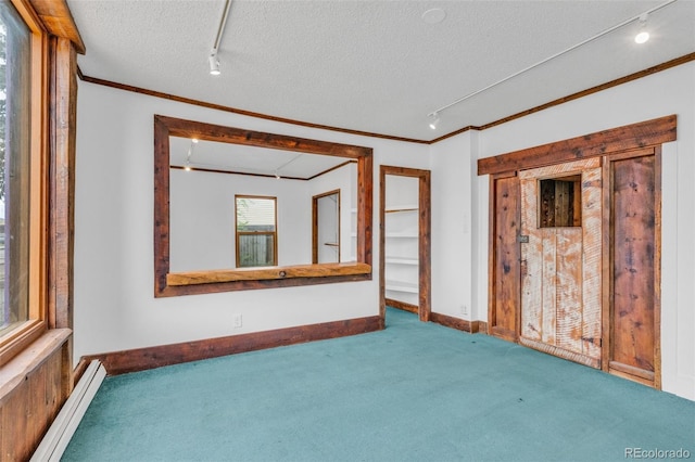 empty room featuring a textured ceiling, carpet, and track lighting