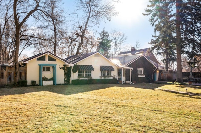 rear view of property featuring a chimney and a lawn