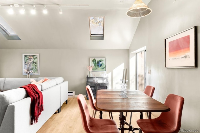 dining area featuring lofted ceiling with skylight, light wood-type flooring, a fireplace, and baseboard heating