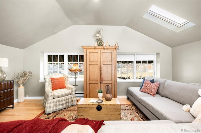 living room with vaulted ceiling with skylight, baseboards, and wood finished floors