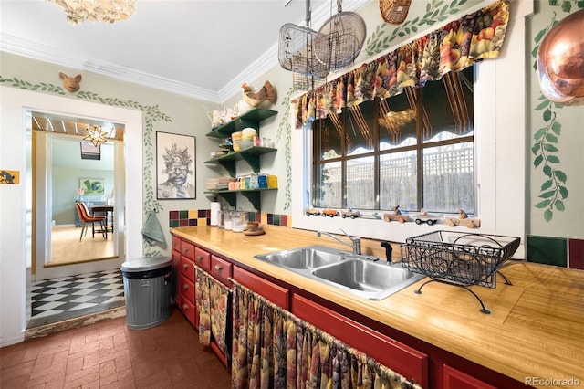 kitchen featuring ornamental molding, brick floor, a chandelier, open shelves, and a sink