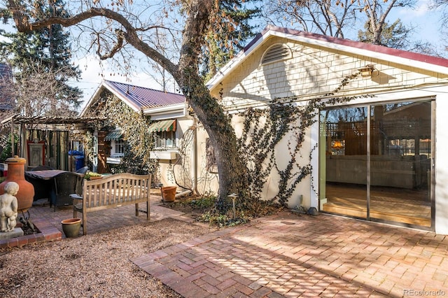 back of property with metal roof and a patio area