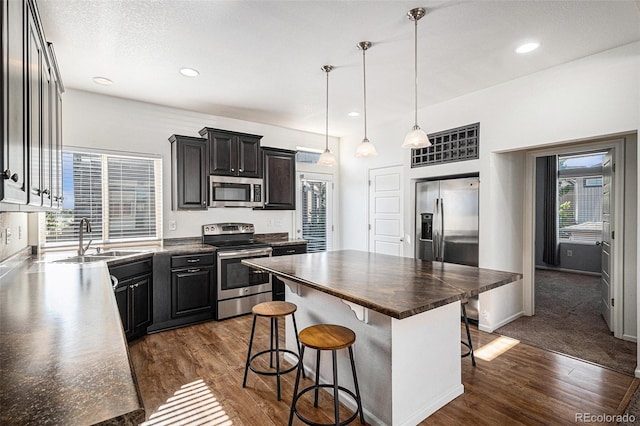 5048 N Andes St, Denver, CO 80249 - kitchen with stainless steel appliances, a breakfast bar area, dark wood-style floors, a kitchen island, and decorative light fixtures