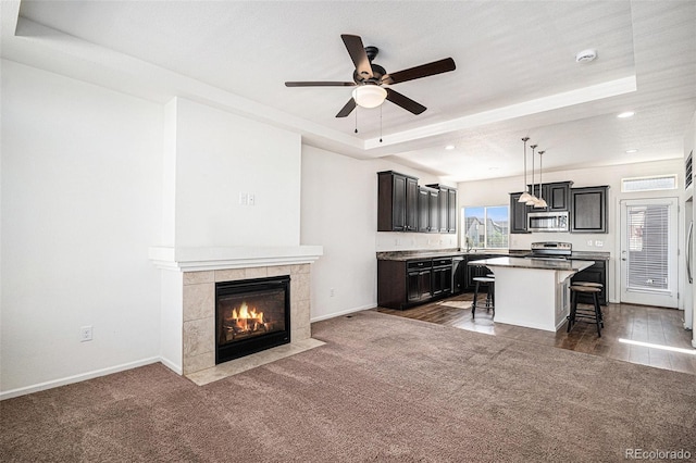 5048 N Andes St, Denver, CO 80249 - kitchen with appliances with stainless steel finishes, a breakfast bar area, a kitchen island, ceiling fan, and a tiled fireplace