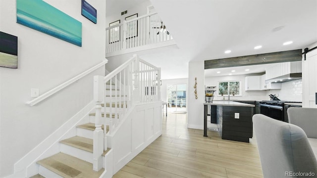 stairway with baseboards, recessed lighting, a barn door, visible vents, and wood finished floors