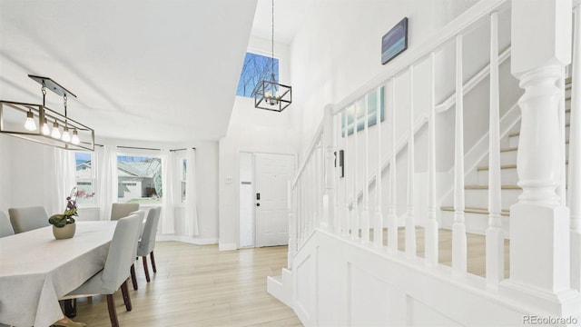 dining space featuring baseboards, an inviting chandelier, a high ceiling, stairway, and light wood-style flooring