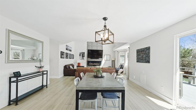 dining room featuring a notable chandelier, light wood-type flooring, and baseboards