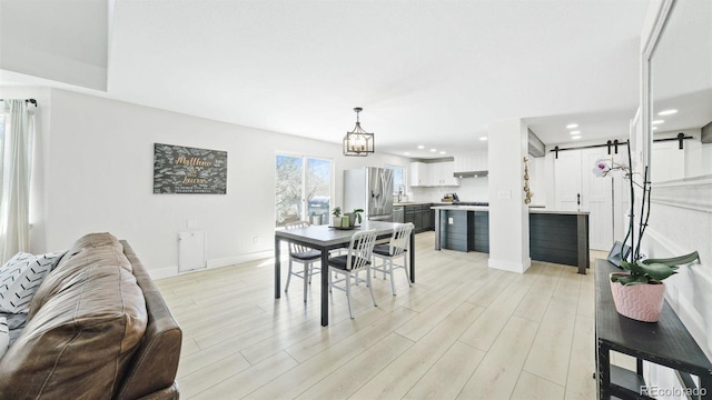 dining area featuring light wood-style flooring, baseboards, and an inviting chandelier
