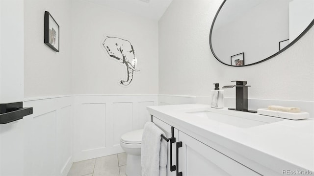 bathroom with a decorative wall, toilet, vanity, and a wainscoted wall