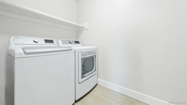 clothes washing area with laundry area, separate washer and dryer, and baseboards
