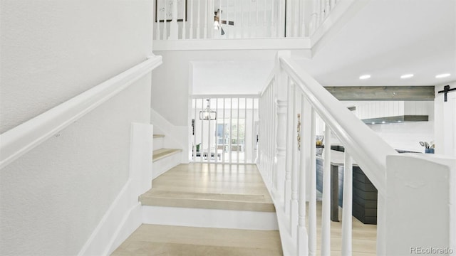 staircase with a barn door and a towering ceiling