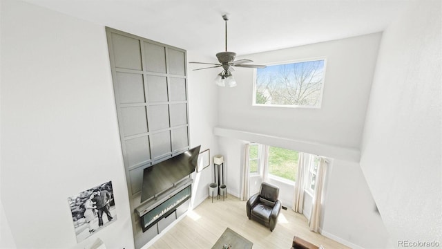 living room featuring light wood-style flooring, ceiling fan, and baseboards