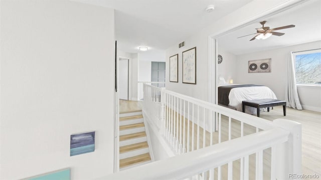 hallway with wood finished floors, baseboards, and visible vents