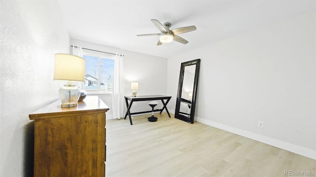 interior space with light wood-style floors, baseboards, and a ceiling fan