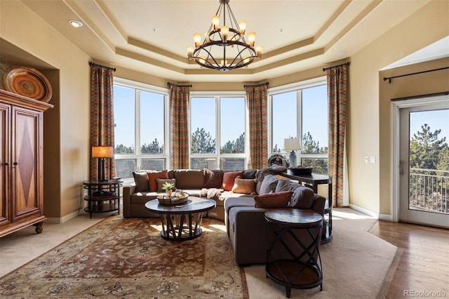 sitting room with baseboards, a chandelier, a raised ceiling, and wood finished floors