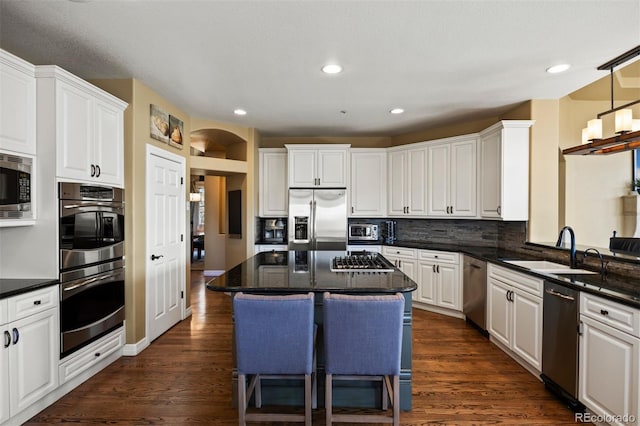 kitchen featuring backsplash, dark wood-type flooring, stainless steel appliances, and a sink