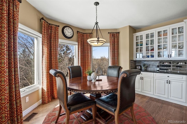 dining space with baseboards, visible vents, and wood finished floors