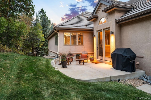 patio terrace at dusk featuring a grill and a yard