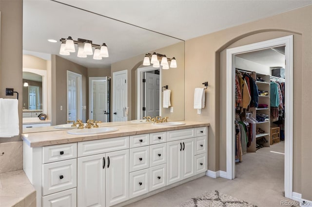 bathroom featuring double vanity, a sink, and a walk in closet