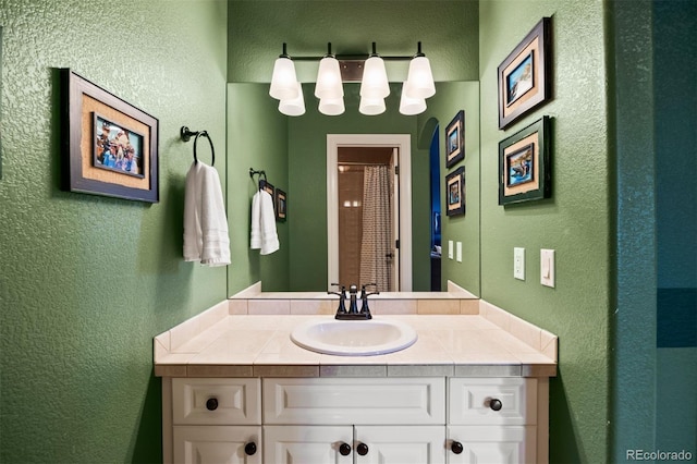 bathroom featuring a textured wall, vanity, and a shower with curtain