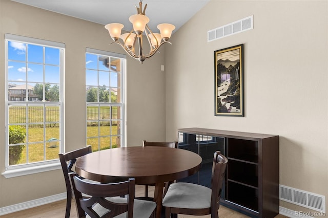 dining space featuring lofted ceiling, light hardwood / wood-style floors, and a chandelier