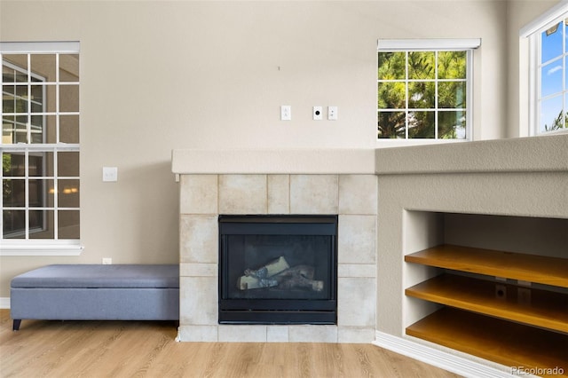 interior details featuring a tile fireplace and wood-type flooring