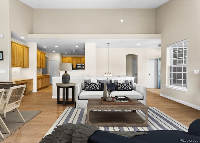 living room with a towering ceiling and light hardwood / wood-style flooring